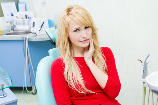 Patient in dental chair holding jaw at  Glen Perio in Glenview, IL