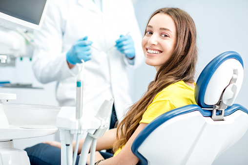 Happy patient sitting in dental chair in front of doctor