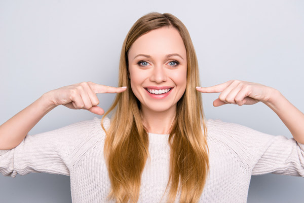 Smiling woman pointing at mouth with both hands in Glenview office.