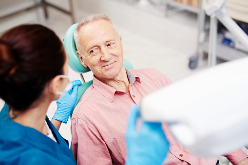 Doctor speaking to patient sitting in dental exam chair