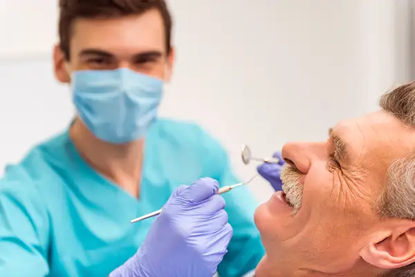 A Periodontist examining the teeth of a happy and comfortable senior patient.